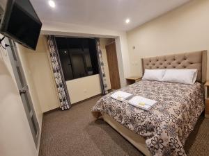 1 dormitorio con 1 cama y TV de pantalla plana en Hostal Tuki Huancayo, en Huancayo