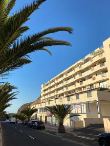 een gebouw met een palmboom voor een straat bij La Arenita - oceanview apartment in Palm-mar