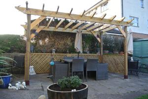 a wooden pergola with a table and chairs under it at Old Castle Farm Guest House in Brecon