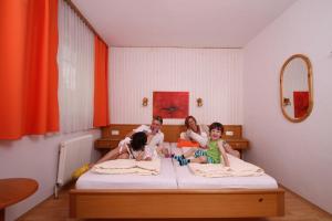 een gezin zit op een bed bij Pension Strohmer in Rust