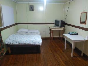 um pequeno quarto com uma cama e uma televisão em Hotel Marruecos C.R. em San José