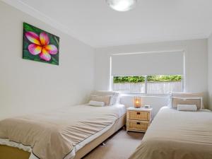 two beds in a white room with a window at Kiama Sunrise Kiama in Kiama