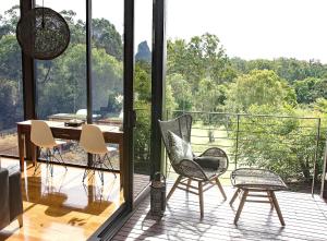 Zimmer mit einem Tisch und Stühlen auf einem Balkon in der Unterkunft Glass On Glasshouse in Glass House Mountains