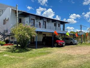 a white house with cars parked in front of it at POSADA SANTA CECILIA in Termas del Daymán