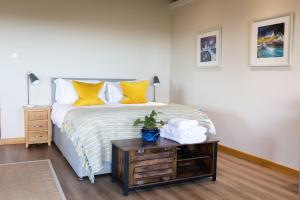 a bedroom with a bed with yellow pillows and a table at The Bothy at Coneloch in Elgin