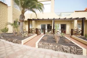 a house with a patio with palm trees at Book Jet - HIBISCUS BEACH FRONT in Costa Calma