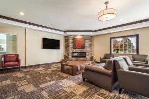 Red Roof Inn & Suites Omaha - Council Bluffs في كاونسيل بلافز: غرفة معيشة مع أريكة وتلفزيون