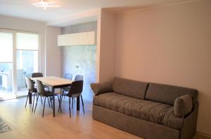 sala de estar con sofá, mesa y sillas en Appartamento Campagnola con giardino privato e due camere da letto, en Riva del Garda