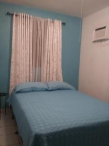 um quarto com uma cama azul e uma janela em Brisas de Borinquen em Aguadilla