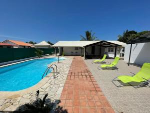 a swimming pool with green chairs next to a house at Casa Du Lac in Kourou