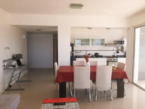 a kitchen and dining room with a red table and white chairs at Costa Mar in Puerto Madryn