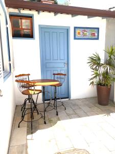 a patio with a table and chairs in front of a blue door at BOA SORTE SUITES com PISCINA, GARAGEM e Pé na PRAIA de GERIBÁ in Búzios