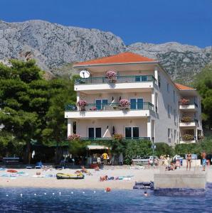 a building on a beach with people on the beach at Villa Dalmatina in Živogošće