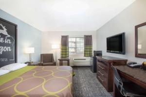 a hotel room with a bed and a flat screen tv at Gateway Inn & Suites Eugene-Springfield in Eugene