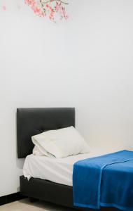 a bed with a black headboard next to a white wall at Wisma 88 in Gorontalo