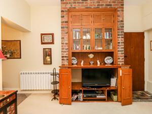a television in a wooden entertainment center in a living room at Old Gaol Cottage in Cerne Abbas