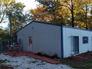 a white shed with a patio and a table at Relaxing Stay in the Country Unit 1 in Ozark