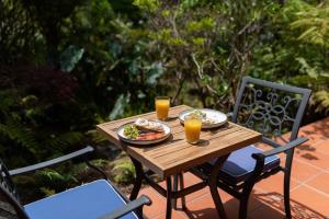 una mesa de madera con un plato de comida y dos vasos de zumo de naranja en Pāteke Lodge, en Kerikeri