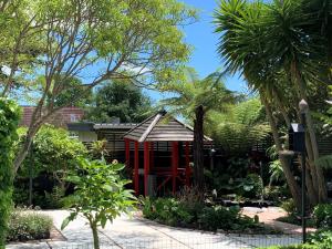 une structure rouge dans un jardin planté de palmiers dans l'établissement Twin Oaks Quiet Cottage, à Paraparaumu