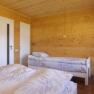 two beds in a room with a wooden wall at На Ґанку in Verkhovyna