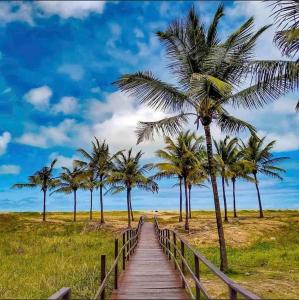 a wooden path leading to a beach with palm trees at Oceano Azul Hospedagens a 50 M DA ORLA-Passarela do Caranguejo in Aracaju