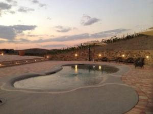 a swimming pool in a patio with a sunset at Cordella in Montalcino Wine Resort in Montalcino