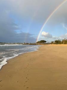 a rainbow over a beach with footprints in the sand at Skippers Apollo Bay in Apollo Bay
