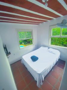 - un lit blanc dans une chambre avec 2 fenêtres dans l'établissement hayway sustentável, à Mendes