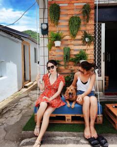 two women sitting on a swing with a dog at 綠島海泡泡的家 in Kung-kuan