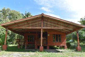 a wooden cabin with a roof on the grass at Pru Valley Thaley Tai Resort in Ban Don Phlap (1)