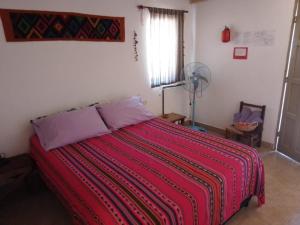 a bedroom with a bed with a red striped blanket at El Cardón,habitación privada en el campo in Humahuaca