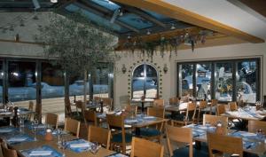 格林德尔瓦尔德Hotel Steinbock Grindelwald的有桌椅和窗户的餐厅