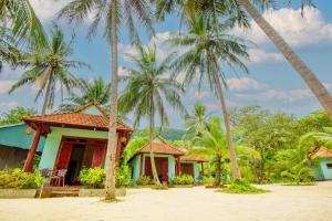 a row of bungalows on the beach with palm trees at Kiki Coconut Beach Resort in Phú Quốc