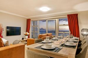 a dining room with a table with chairs and a living room at Beach penthouse-style living,self checkin,king beds in Cape Town