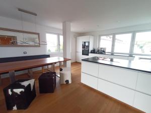 eine Küche mit weißen Schränken und einem Holztisch in der Unterkunft BodenSEE CITY APARTMENTS Friedrichshafen in Friedrichshafen