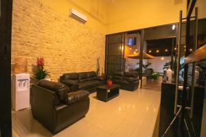a living room with leather furniture and a brick wall at Hotel Avila in Valladolid