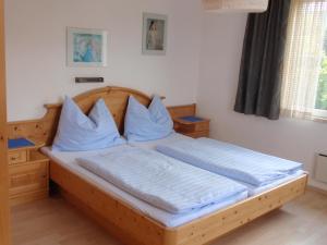 una camera con letto in legno e cuscini blu di Ferienwohnungen Kern a Weyregg