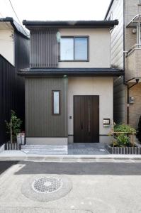 une maison avec une porte marron et une allée. dans l'établissement Ya -MIYABI, à Kyoto