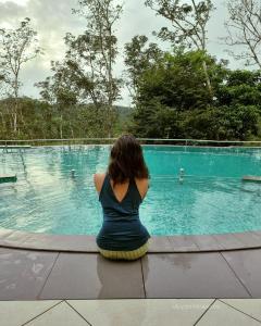 a woman sitting in front of a swimming pool at Serene Crest Resort in Mananthavady