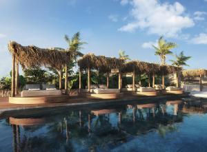 a resort with a pool with chairs and straw umbrellas at Charisma Hotel and Wellness Suites in Plintri