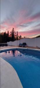 ein blauer Pool mit Sonnenuntergang im Hintergrund in der Unterkunft Casa Benamahoma in Benamahoma