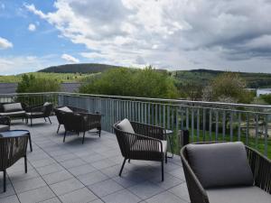 eine Terrasse mit Stühlen und Tischen auf dem Balkon in der Unterkunft Hotel FÜNF10 in Netphen