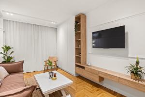 uma sala de estar com um sofá e uma televisão na parede em Little Athens em Atenas