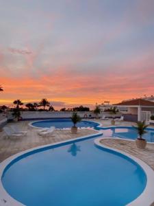 a large swimming pool with a sunset in the background at BuenaVista Romantic Bungalow in Costa Adeje in Adeje