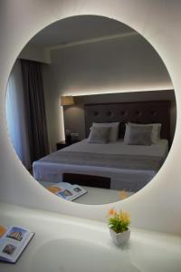 a bedroom with a bed with a round mirror at Oscar Hotel in Laganas