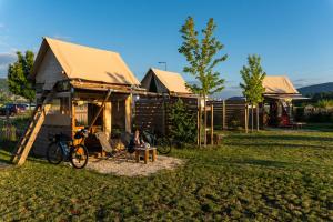 une personne assise sur une chaise devant une maison dans l'établissement Les Lodges de la ViaRhôna - Tentes Lodges, à Virignin