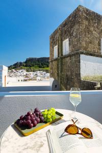 una mesa con un plato de uvas y una copa de vino en Villa Dafni - Lindos, en Lindos