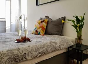a bed with a plate of fruit and two glasses of wine at New Pest Apartman in Budapest
