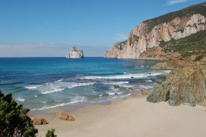 a beach with a large rock in the ocean at Agriturismo Agrifoglio in San Giovanni Suergiu