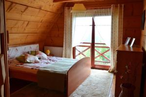 a bedroom with a bed and a large window at Góralska Ostoja - tradycyjny, drewniany dom na Kudłaczach, duży ogród, piękna panorama, sauna, jacuzzi in Pcim